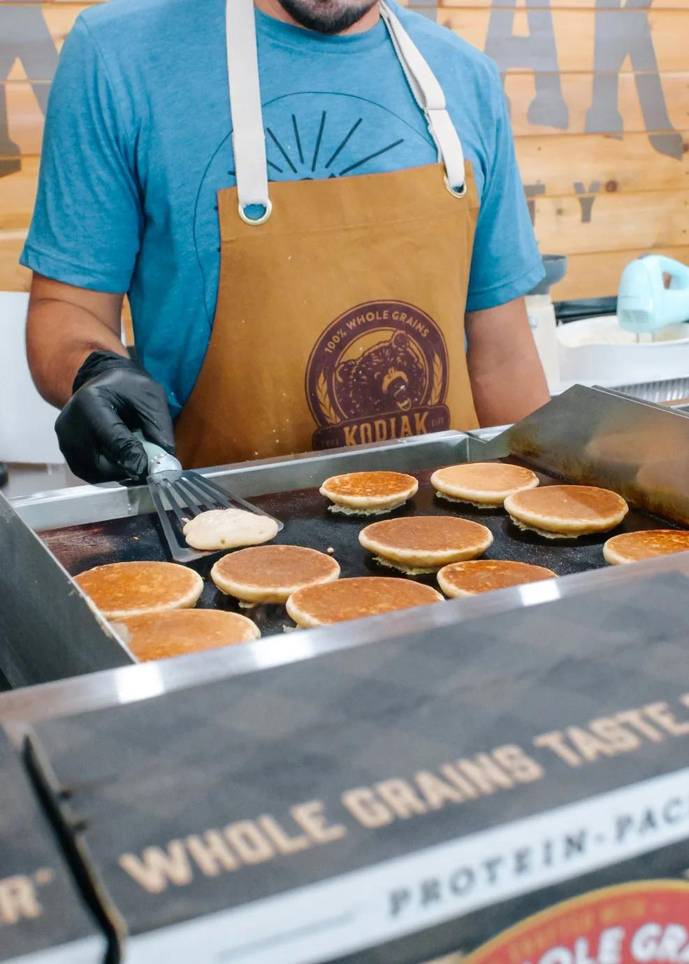 Image of Kodiak Cakes brand ambassador cooking pancake samples at a CPG sampling event