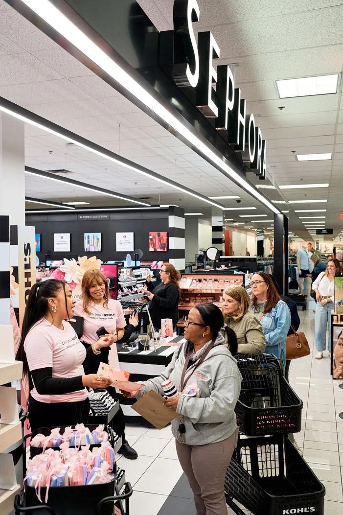 Image of Sephora and Kohl's staff assisting a line of shoppers at an in-store beauty event display counter