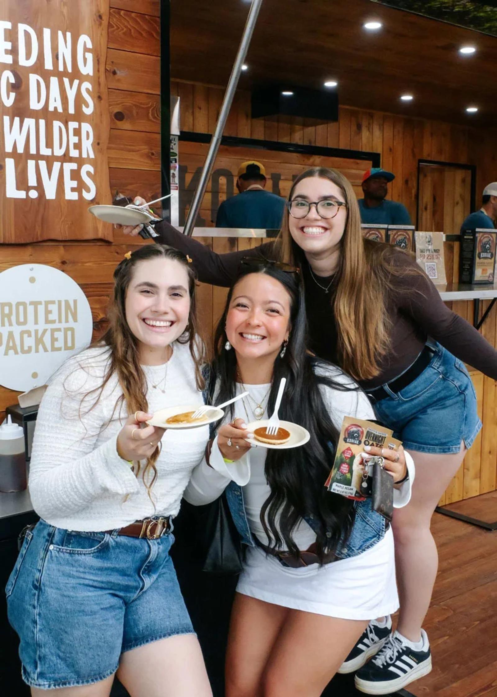 Image of three women holding pancake samples at a Kodiak Cakes brand activation booth