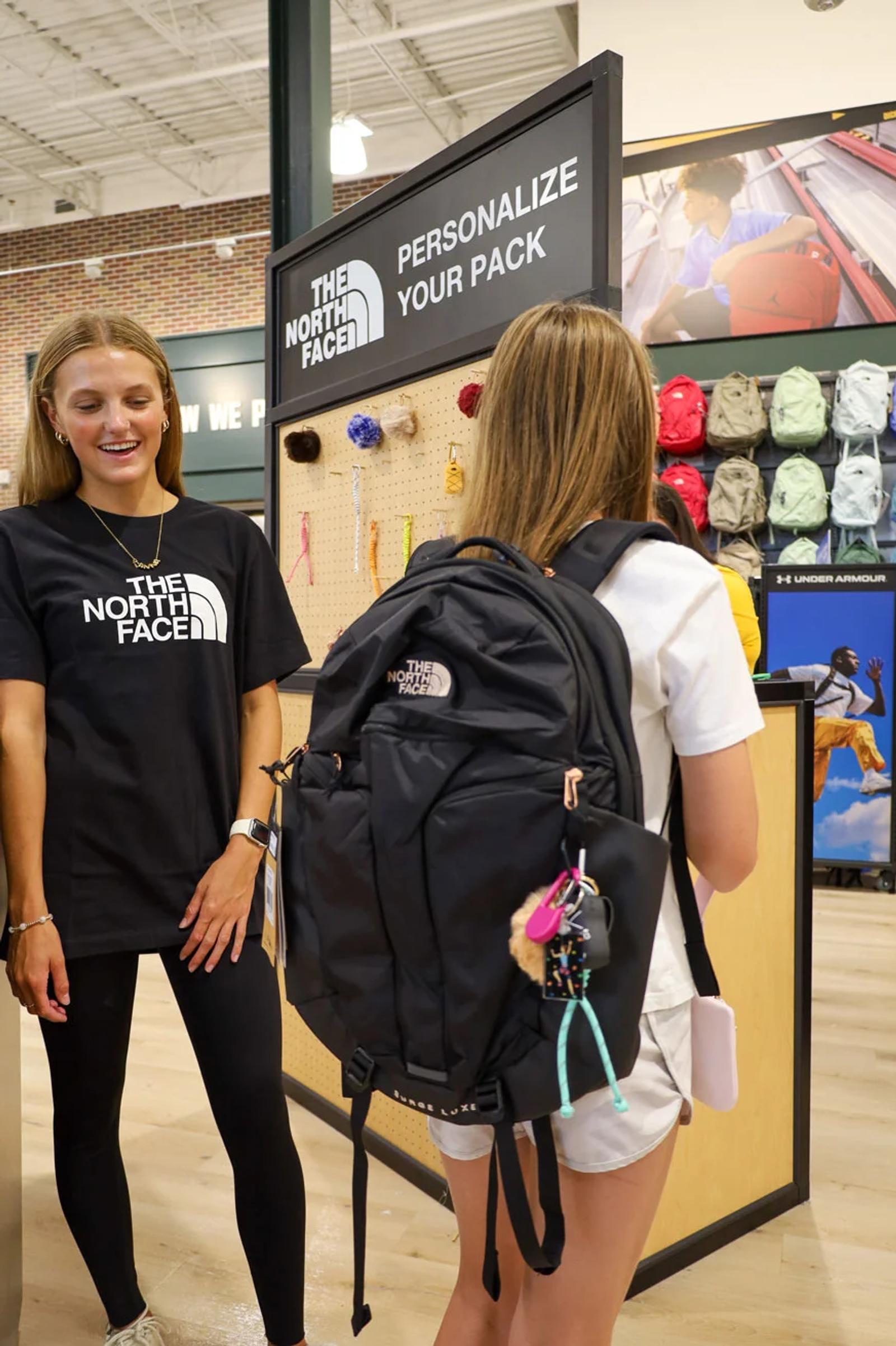 Image of a North Face associate helping a customer personalize a backpack at the Personalize Your Pack station