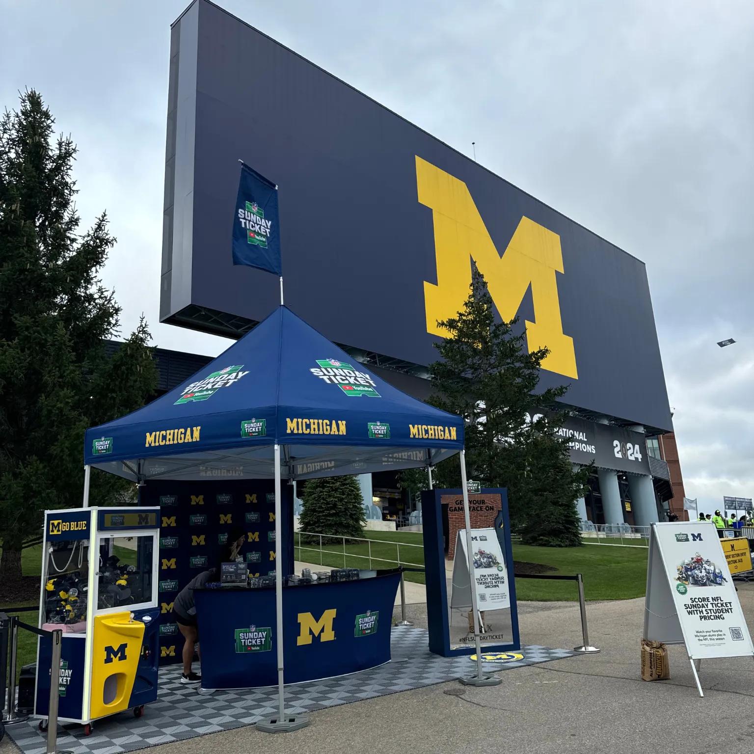 Image of the YouTube NFL Sunday Ticket activation footprint outside Michigan Stadium with a tent and claw machine