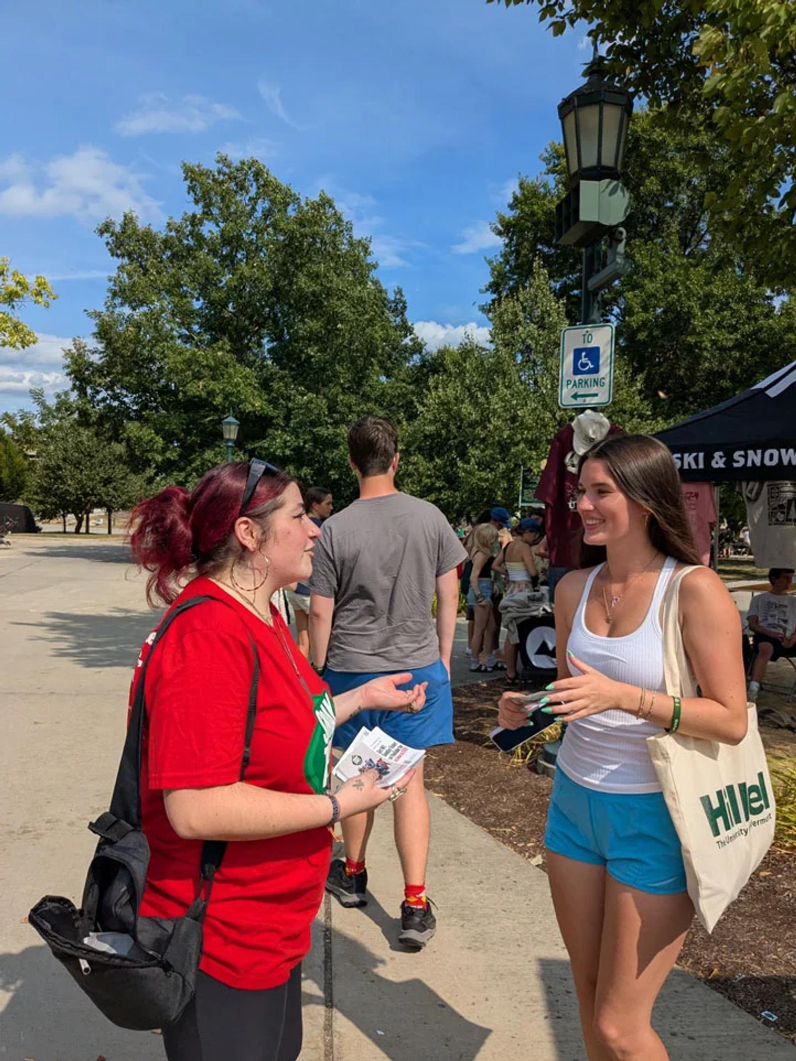Image of a brand ambassador engaging a college student at an outdoor campus marketing event