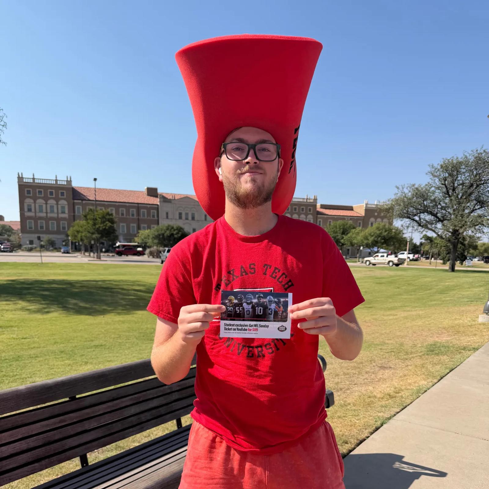 Image of a Texas Tech student in a foam hat holding a YouTube NFL Sunday Ticket $119 student offer card