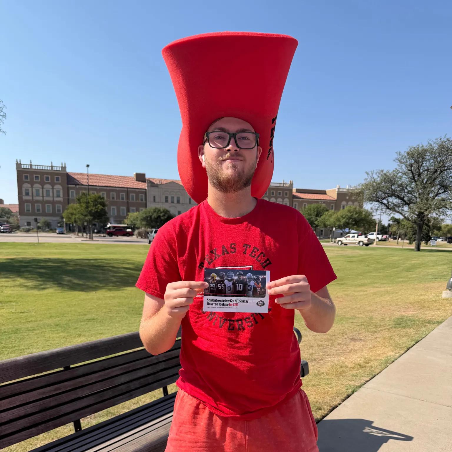 Image of a Texas Tech student in a foam hat holding a YouTube NFL Sunday Ticket $119 student offer card