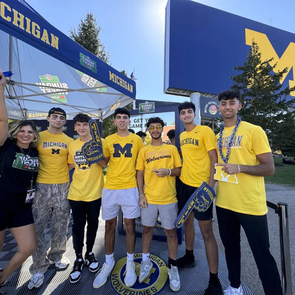 Image of Michigan students posing with foam fingers at the YouTube NFL Sunday activation tent