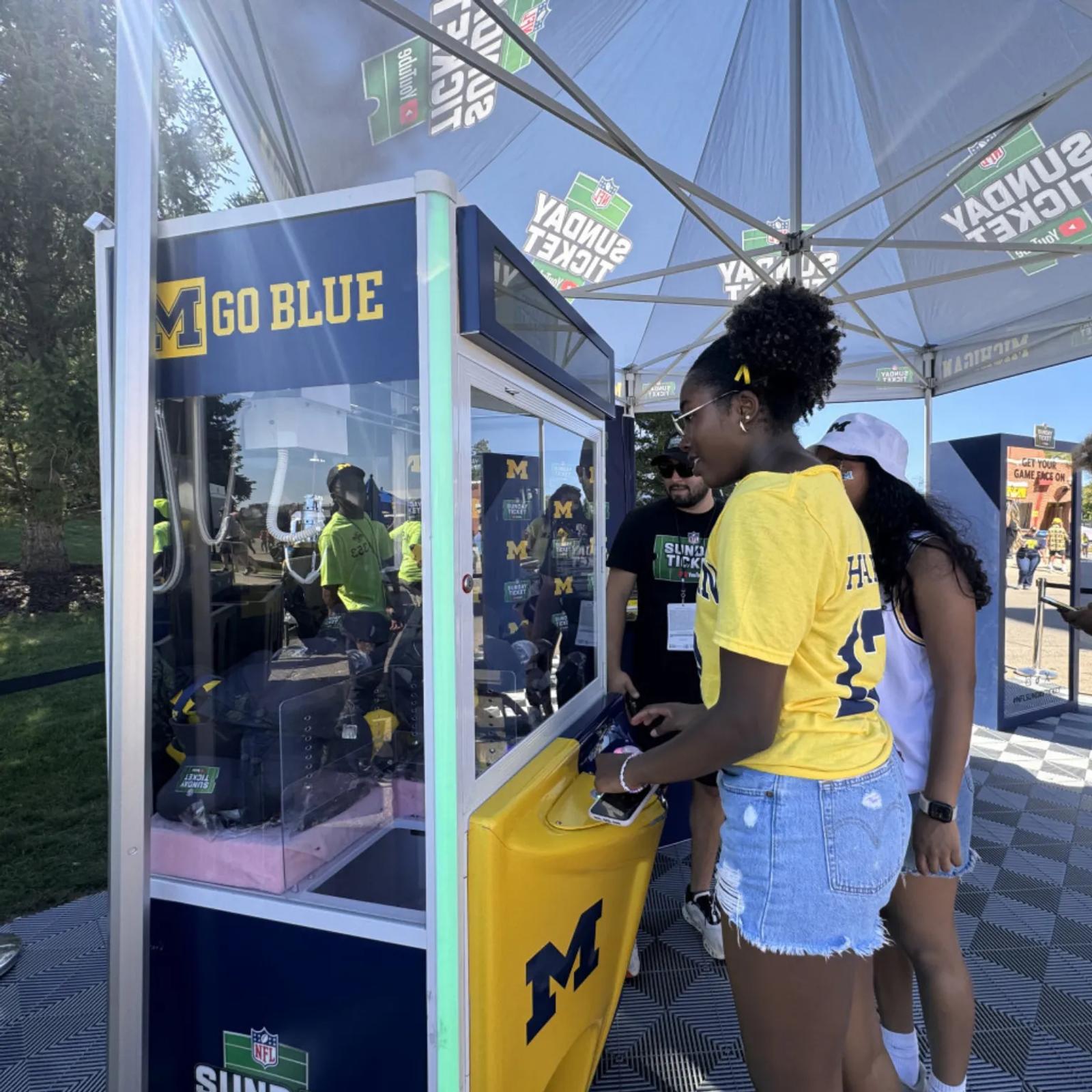 Image of Michigan students playing a branded claw machine at a YouTube NFL Sunday Ticket campus activation