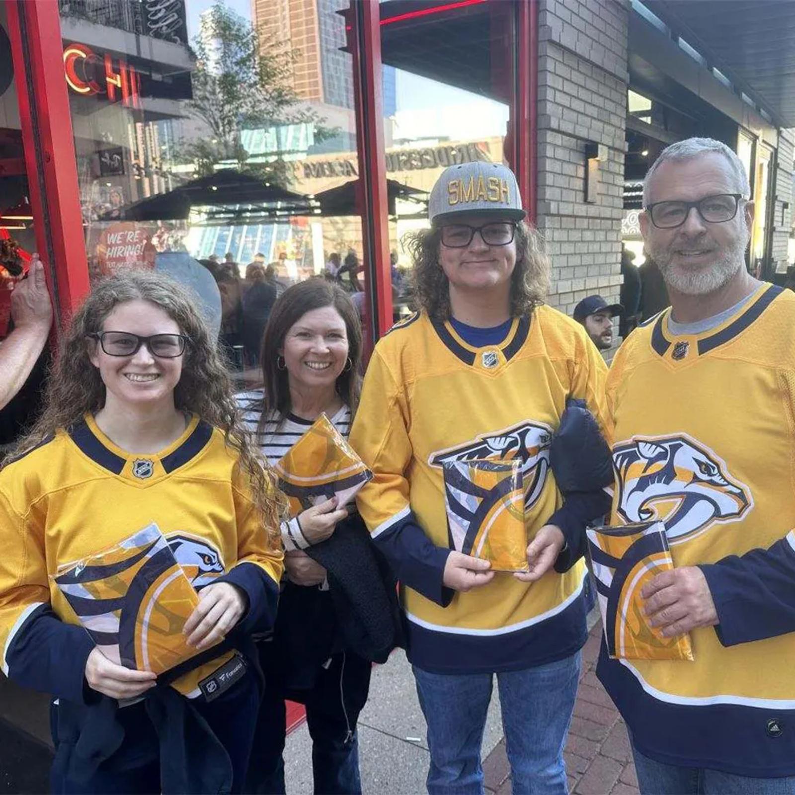 Image of Nashville Predators fans in gold jerseys holding branded giveaways outside the arena