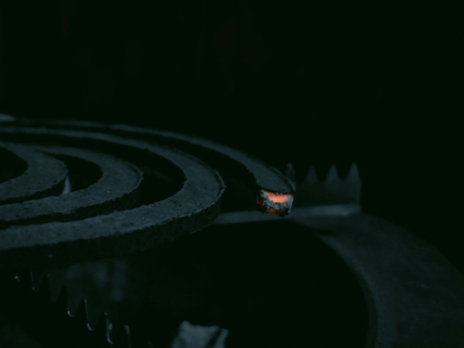 A lit mosquito coil burning in the dark.