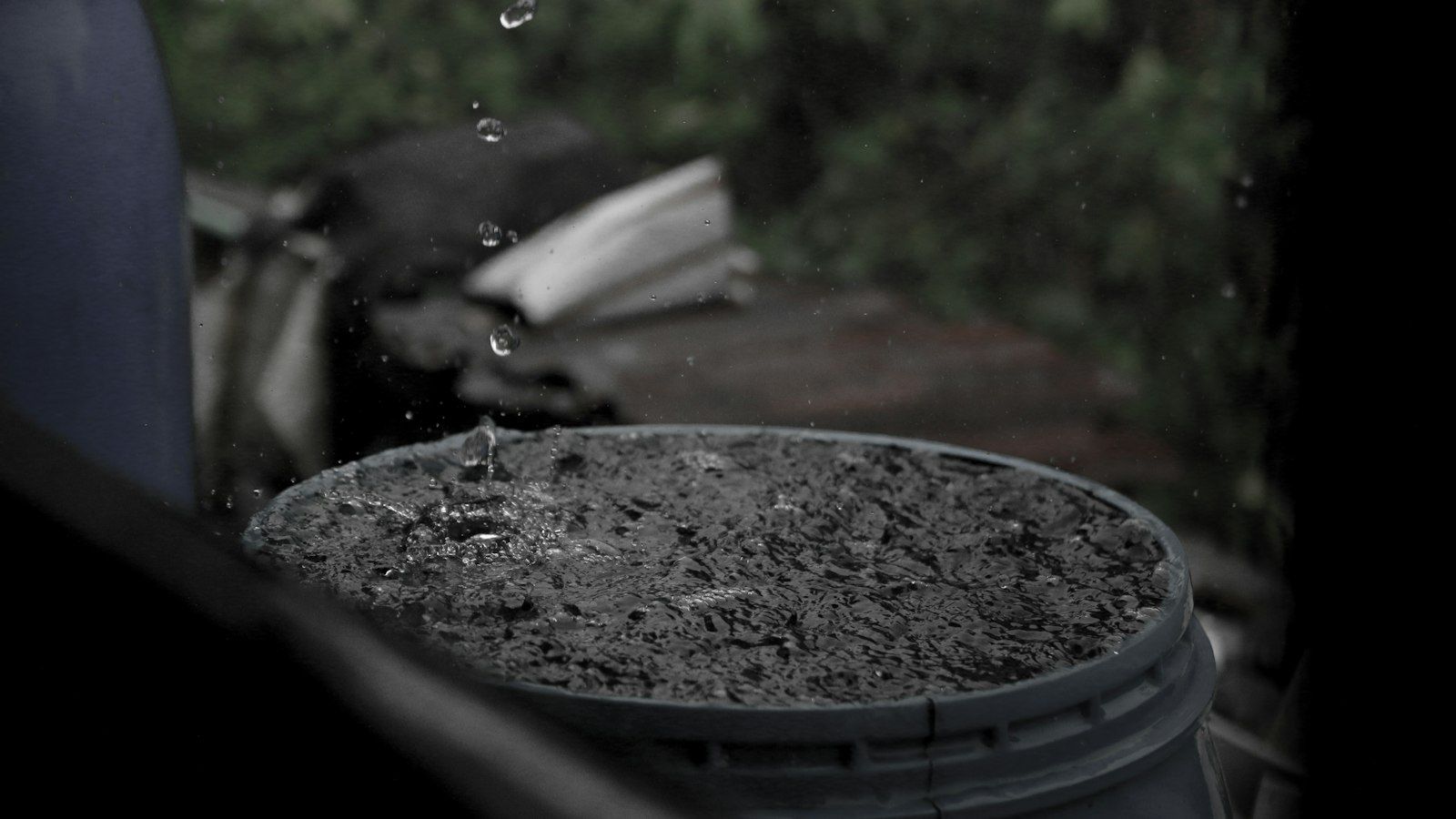 Rain falling into a water-filled plastic barrel