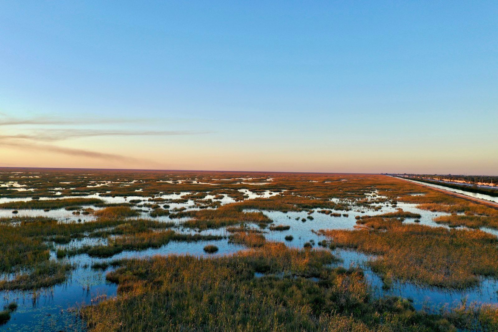 Expansive wetland landscape under a clear sky at dusk