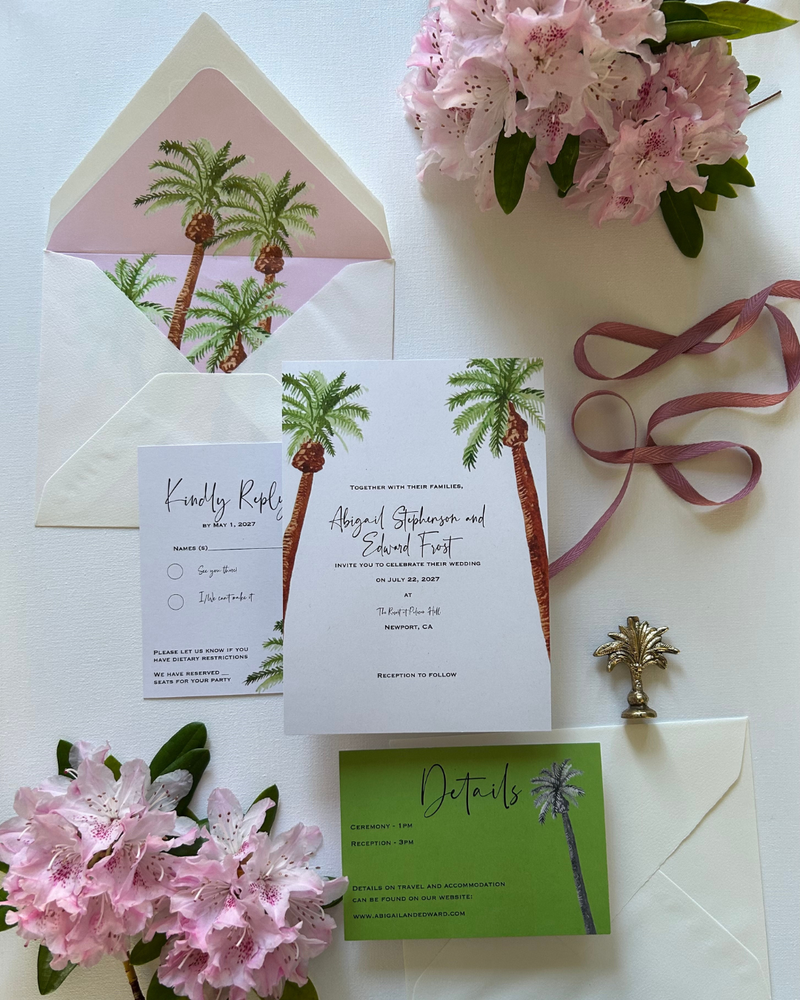 palm-tree-invitation-suite-lying-flat-on-a-white-surface-with-flowers
