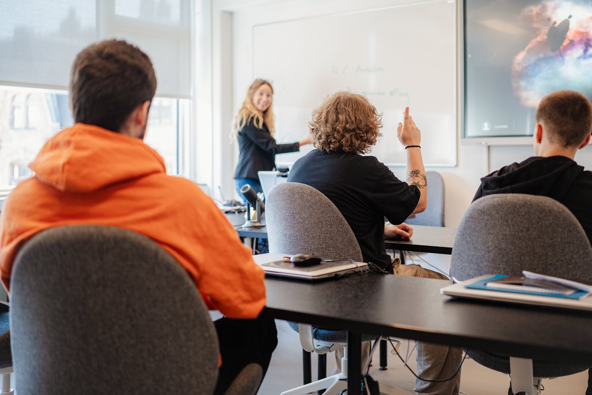 Undervisning i klasselokalet: underviseren gennemgår stof ved whiteboardet, mens eleverne følger med