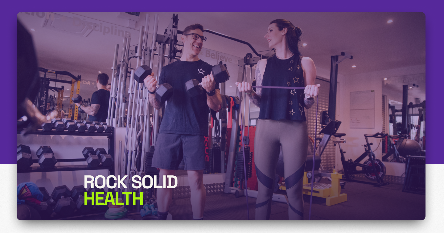 Two people training with dumbbells in the gym, under the Rock Solid Health wordmark