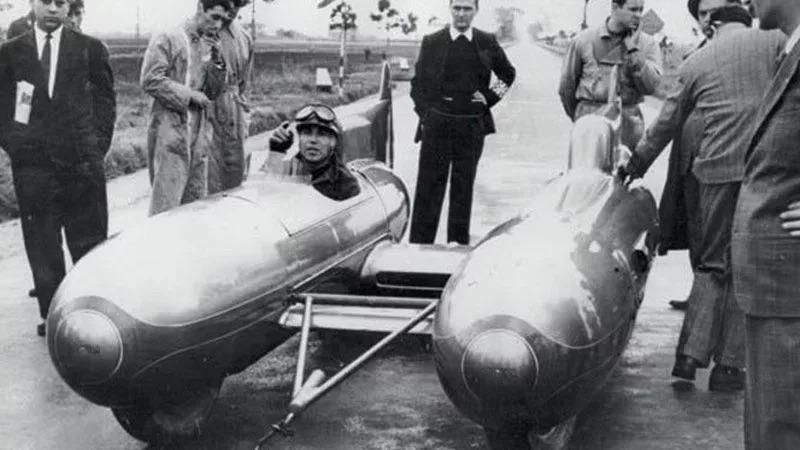 Racing driver in a race car with several people around it