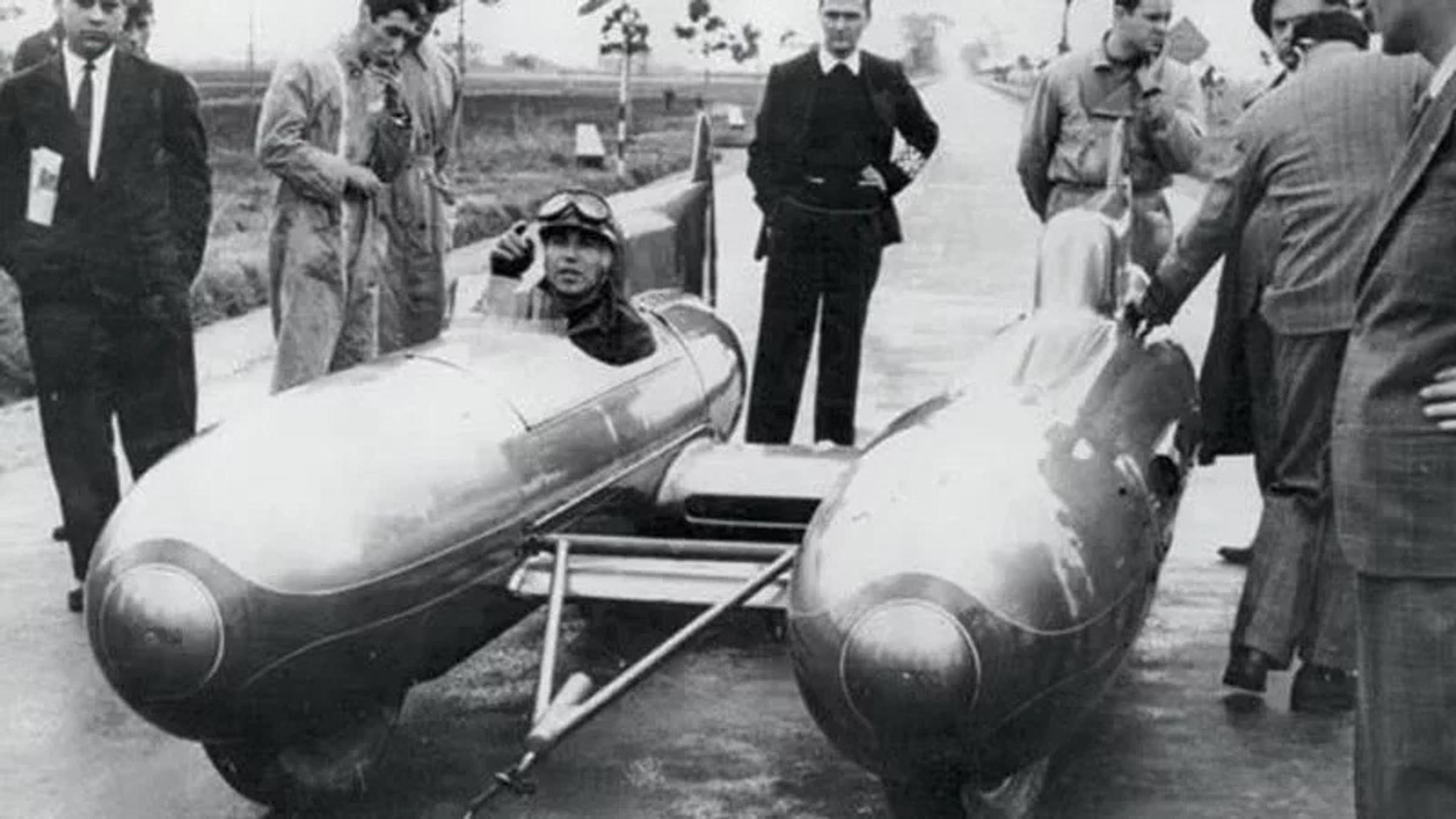 Coureur in racewagen met meerere mensen er omheen