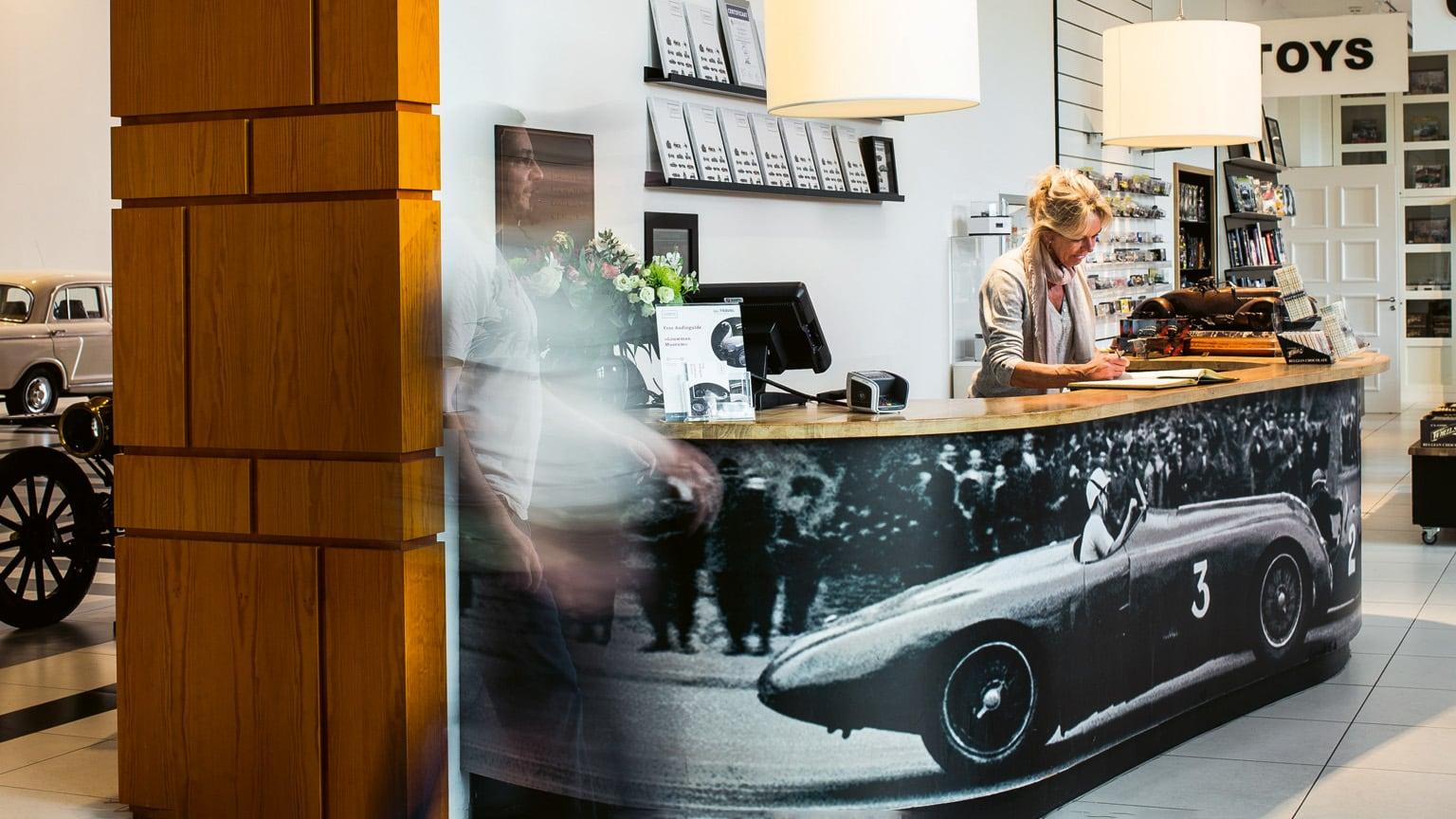 Woman behind the counter of the museum shop with a picture of a race car on it