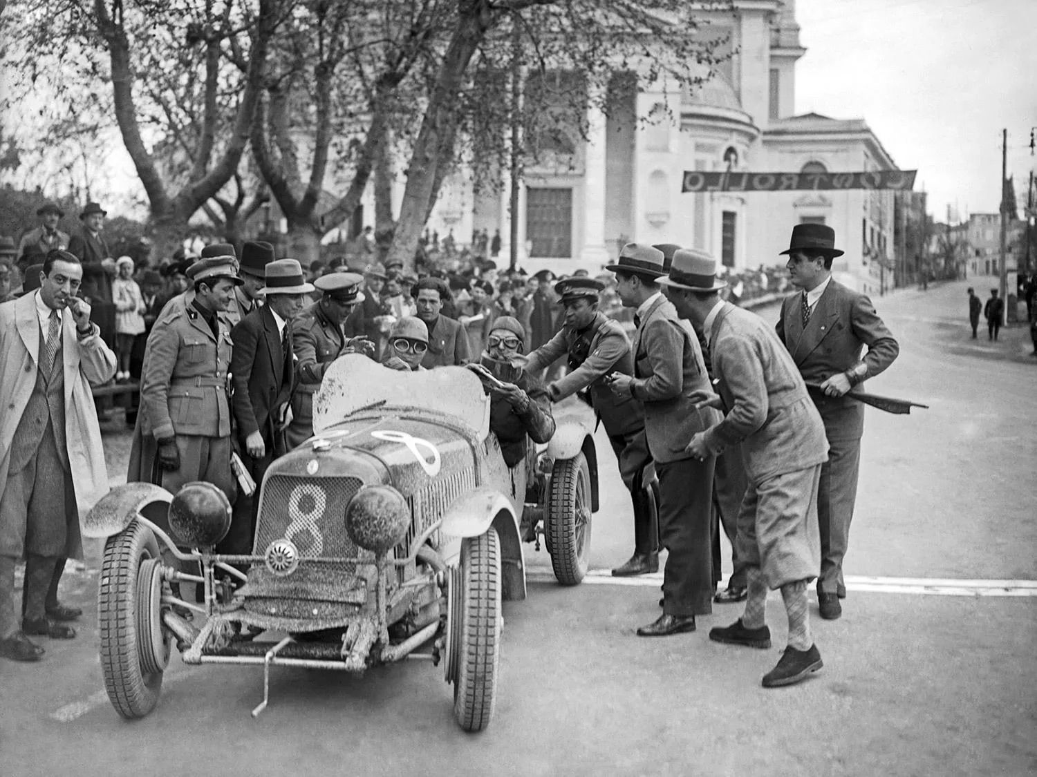 Raceauto met twee coureurs en groep mensen er omheen