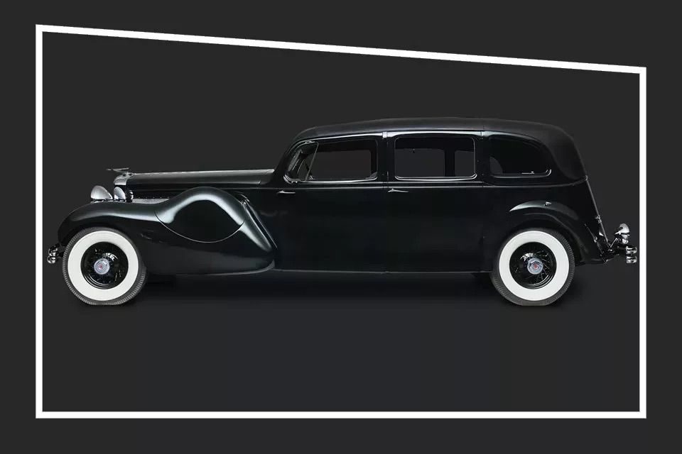 Black car with white tyres seen from the side in a black studio