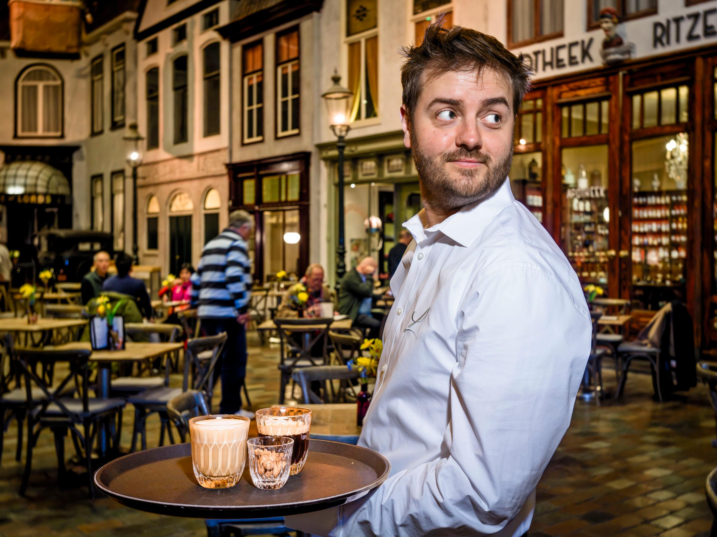 Ober met dienblad met koffie op het museumplein in het museum