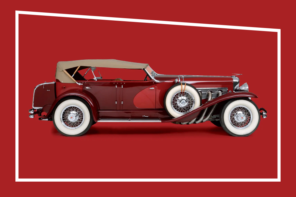 Rotes Duesenberg Auto mit weissen Raedern und beigem Verdeck Seitenansicht im roten Studio