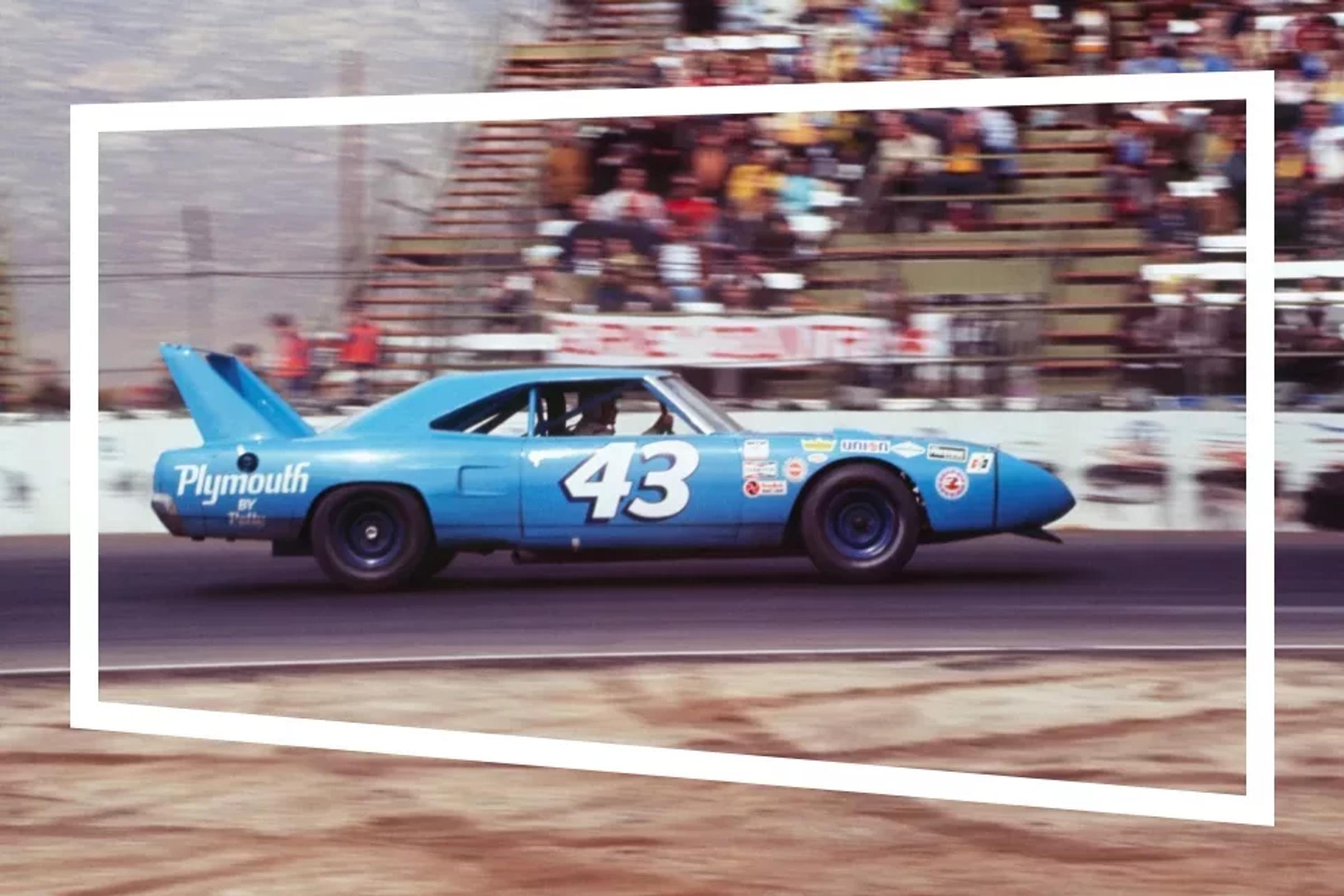 Blauwe Plymouth Road Runner rijdend over een circuit met vage tribune op achtergrond