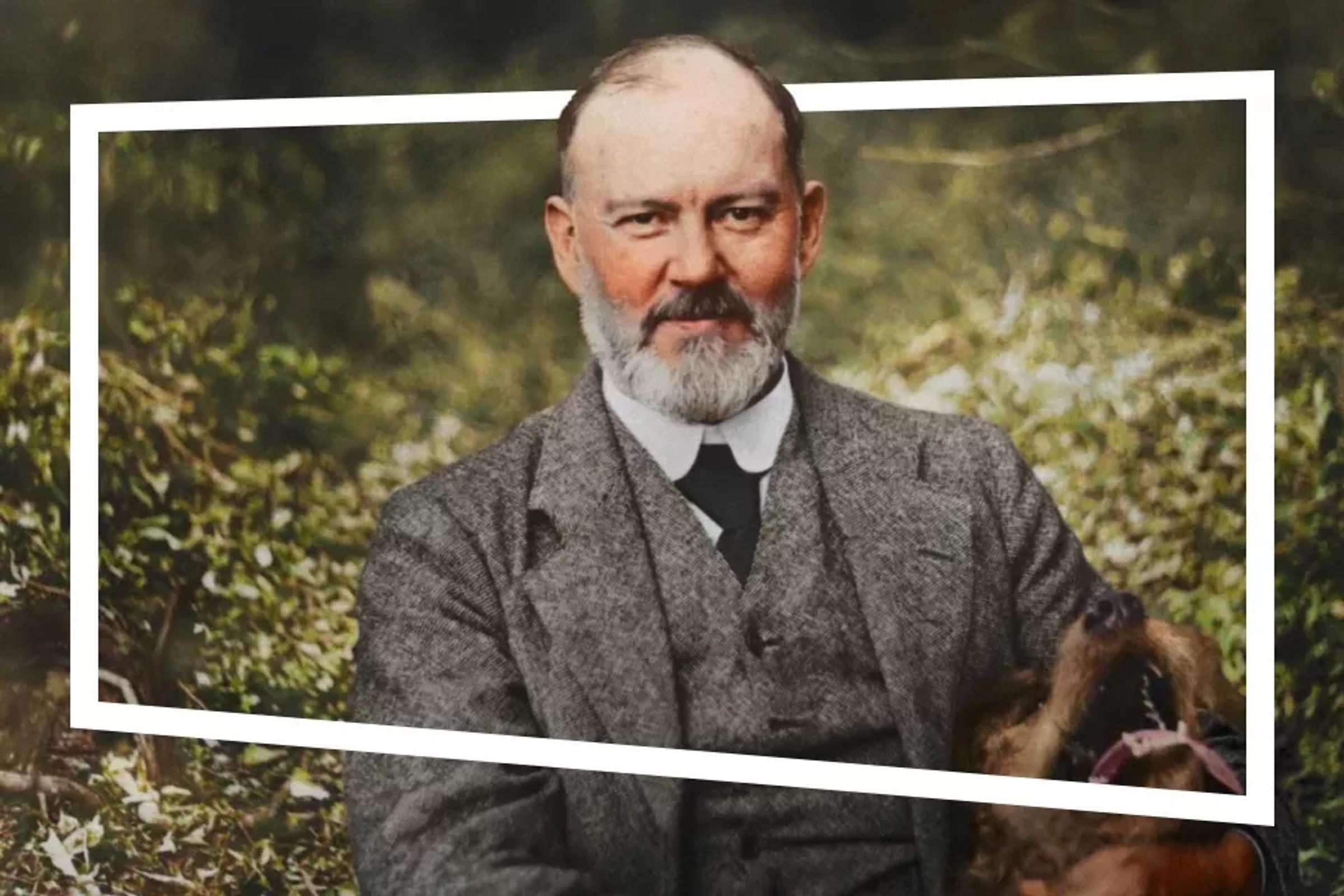 Portret van man met baard in pak met groene achtergrond en een kop van een hond