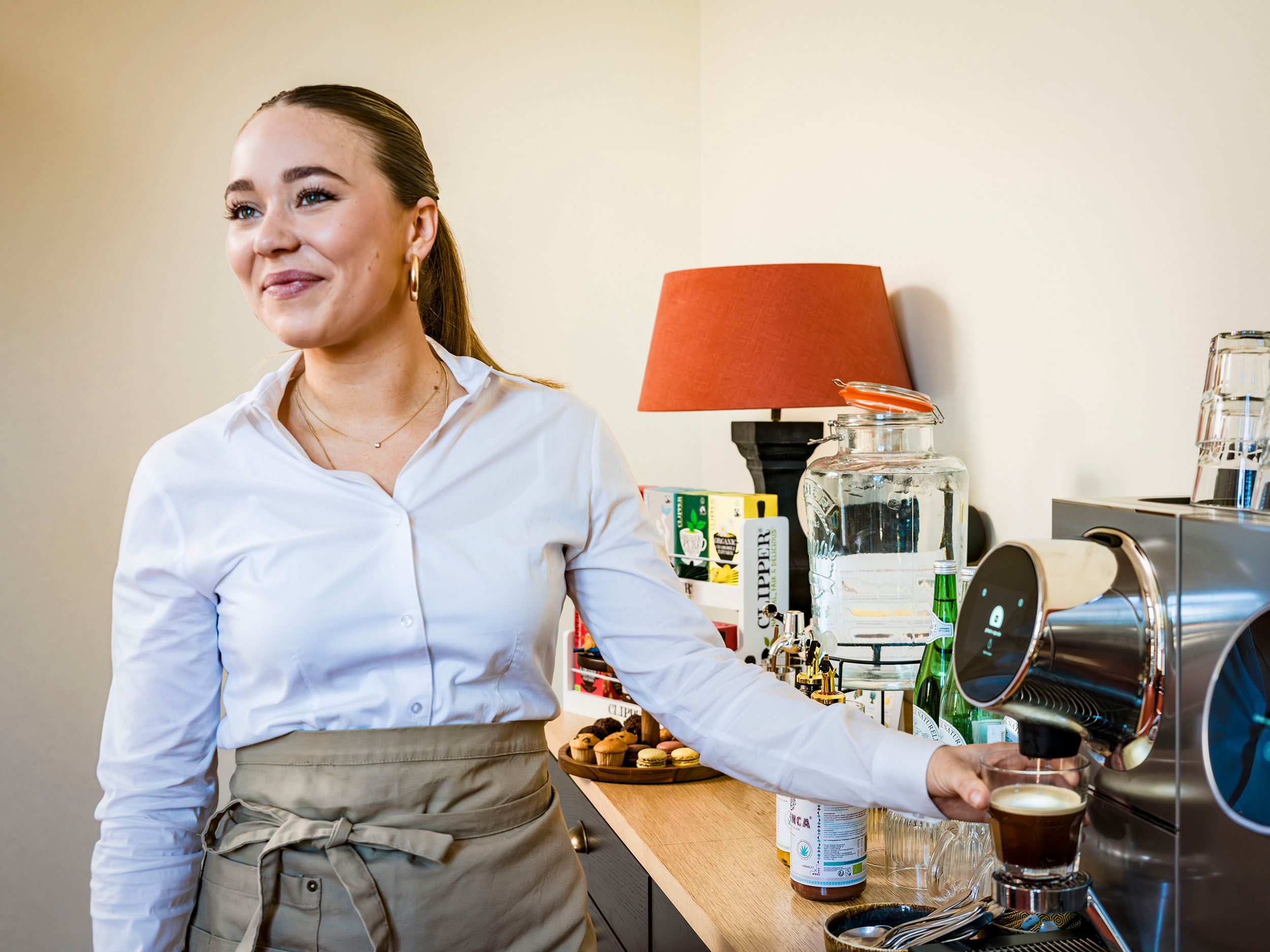Serveerster bij koffiemachine