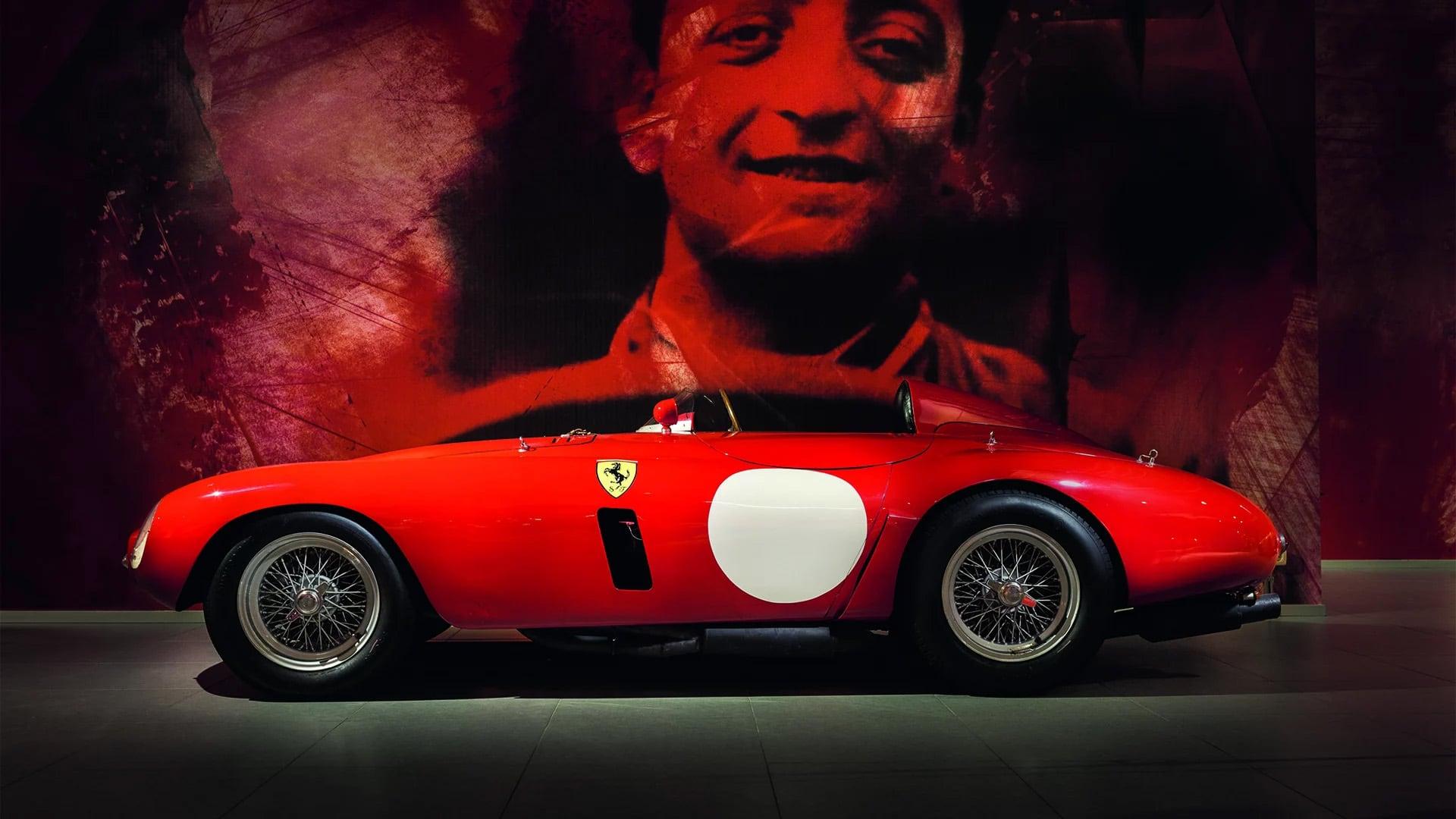 Rode Ferrari in donkere ruimte met grote foto van coureur op de achterwand