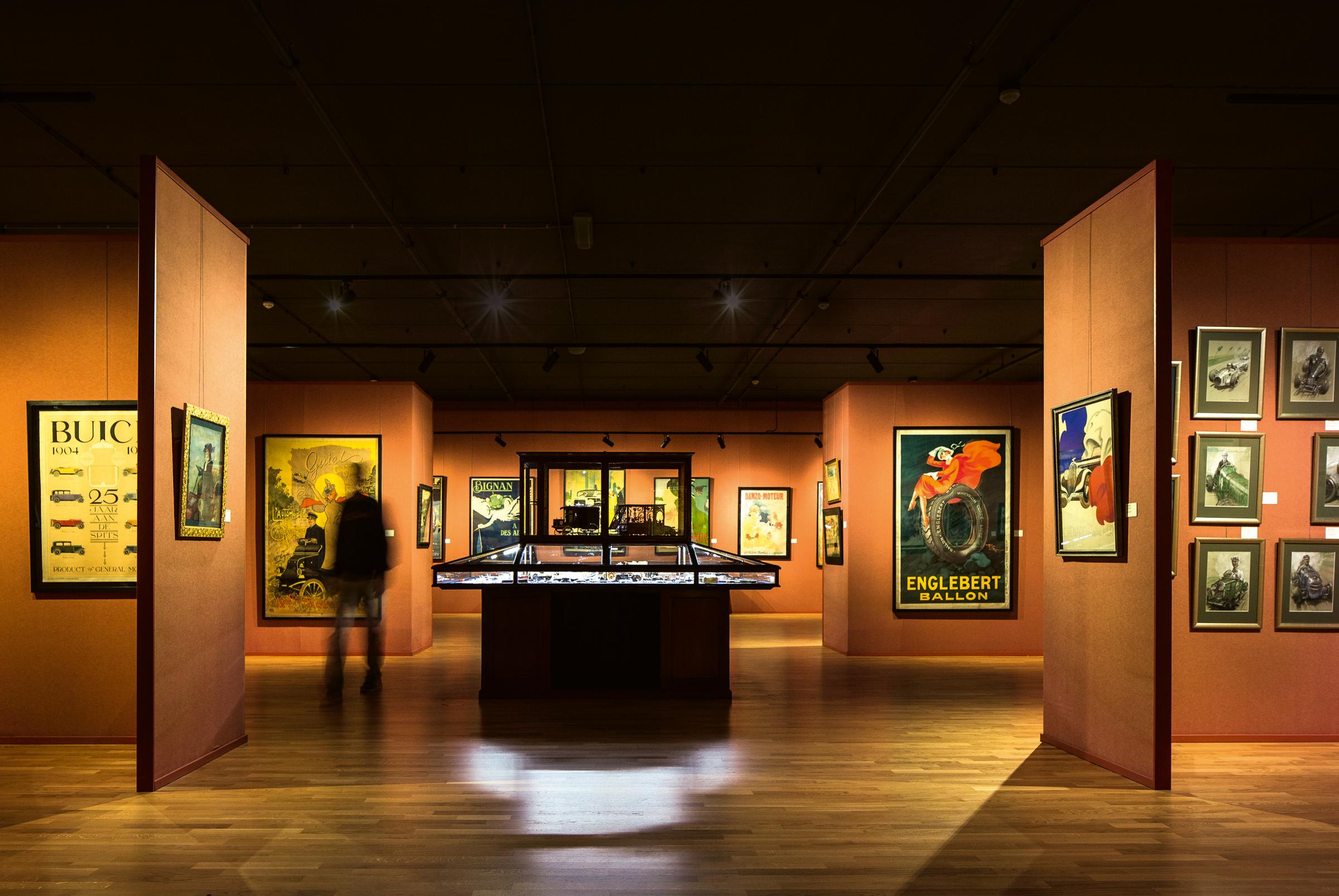 Oranje zaal met kunst aan de wanden en vitrinekast in het midden