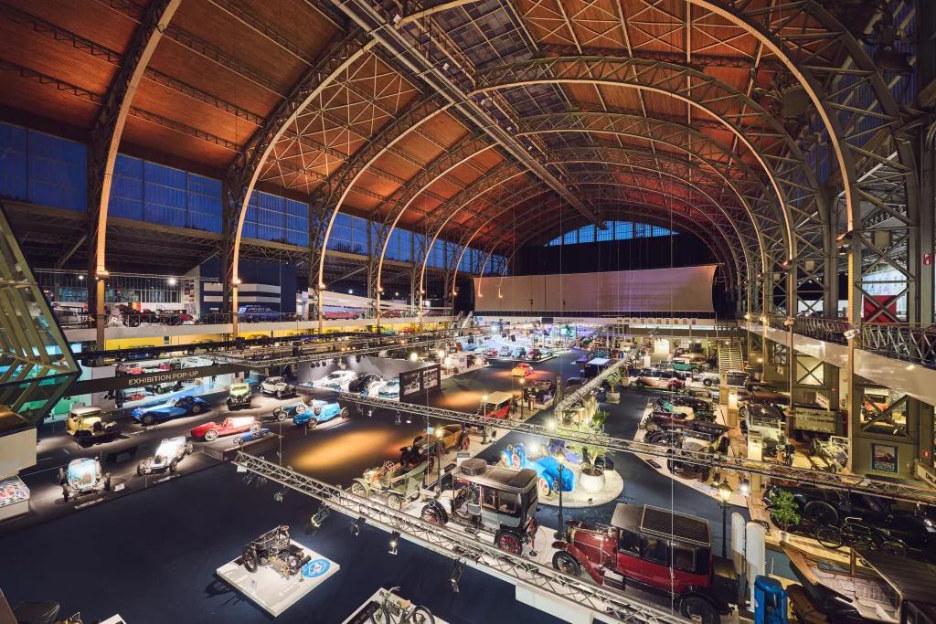 De grote hal van Autoworld in Brussel waar auto's geëxposeerd staan.