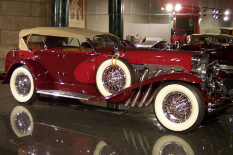 Rode auto met beige wielen en dakje in glimmende showroom