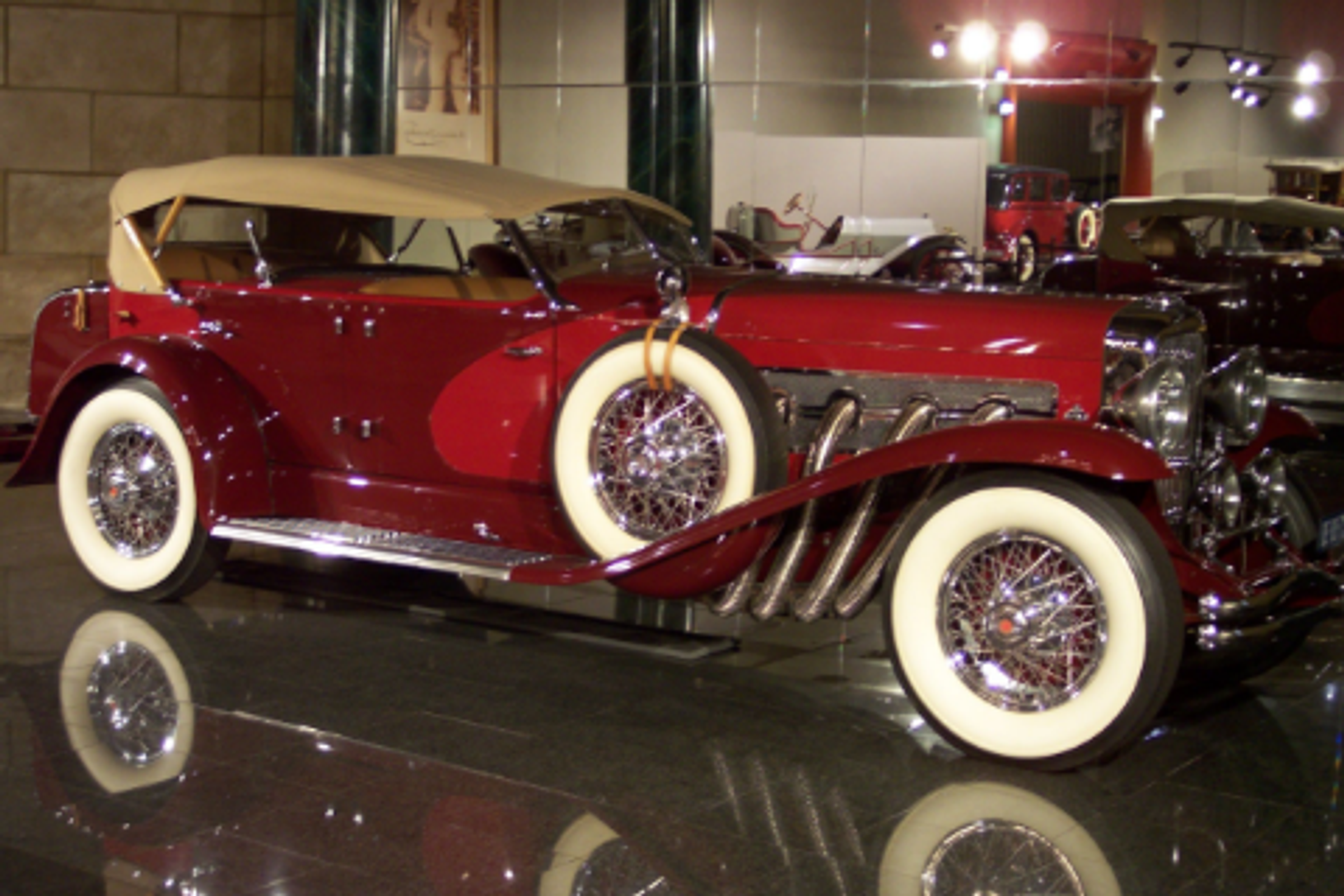 Red car with beige wheels and roof in a gleaming showroom