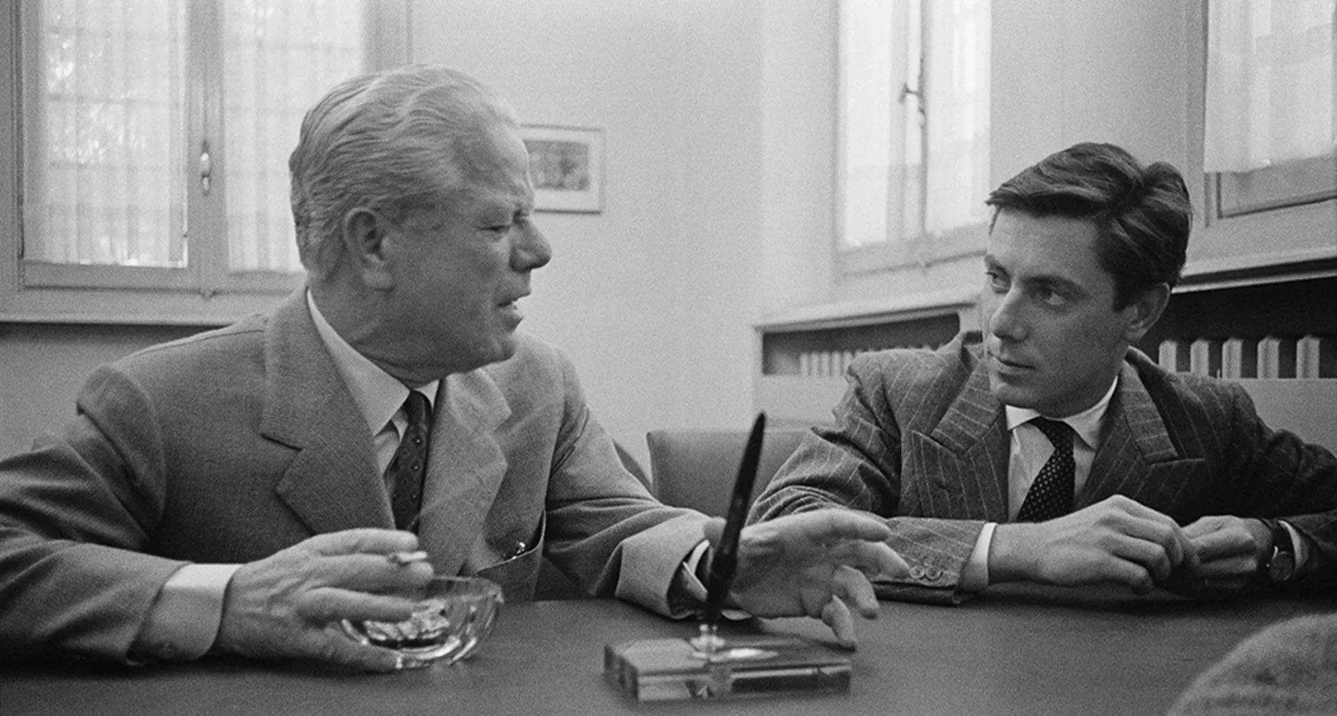Twee mannen aan bureau in een kantoor met pen in penhouder op de voorgrond