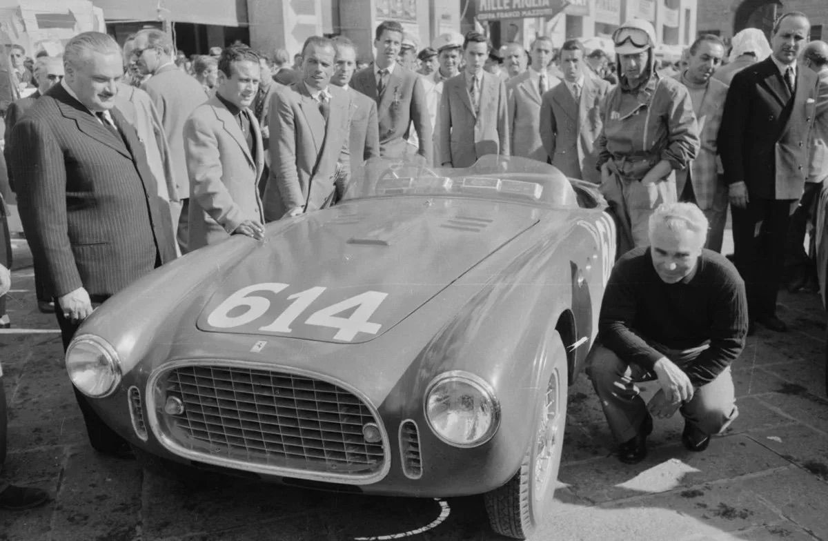Piero Taruffi gehurkt naast raceauto
