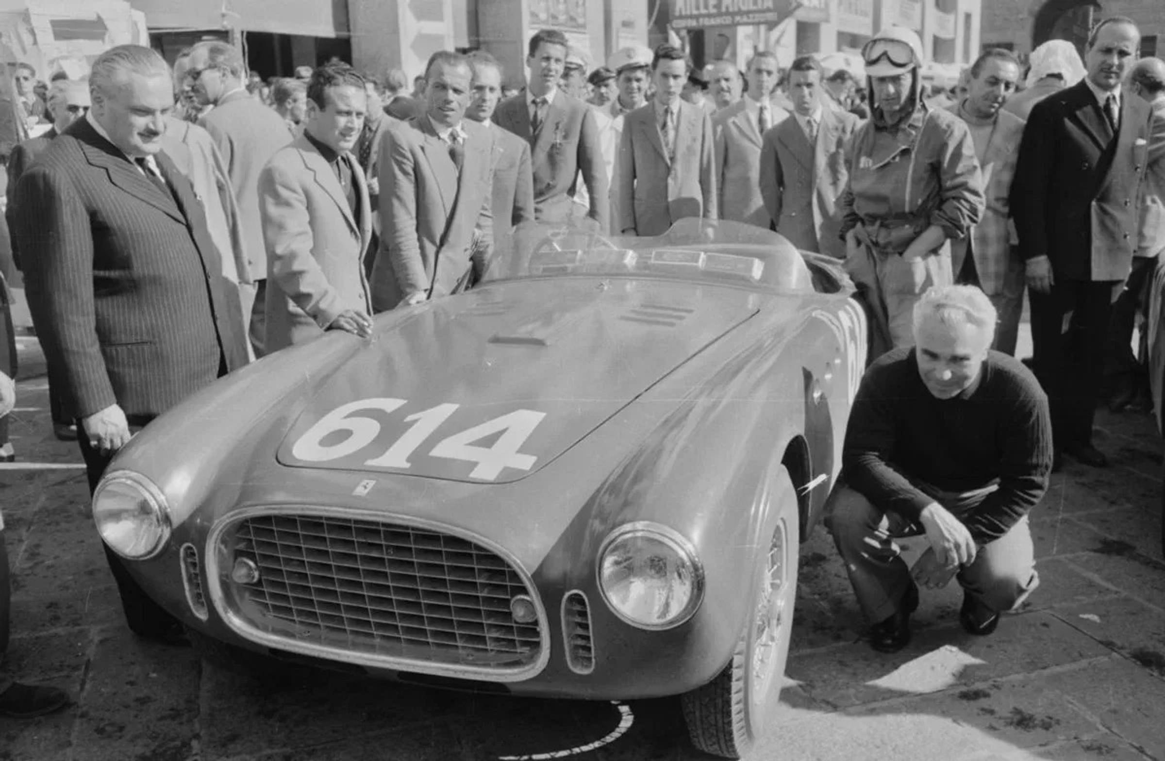 Piero Taruffi gehurkt naast raceauto