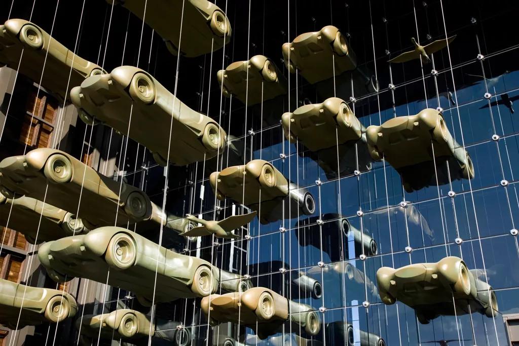 Voorgevel van Musée National de l'Automobile met auto kunstwerken aan kabels door de ruiten