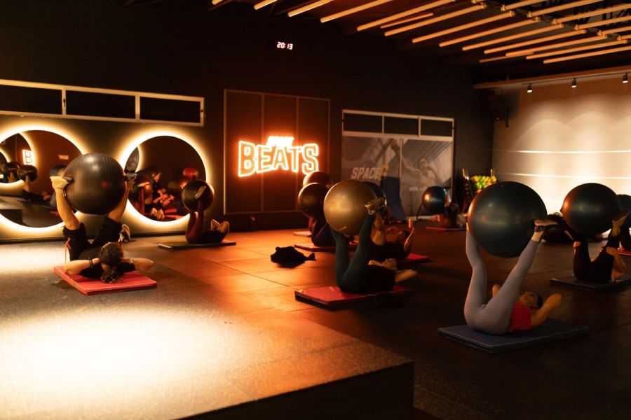 Alumnas de Pilates con el balón entre los pies frente al letrero de la sala Beats