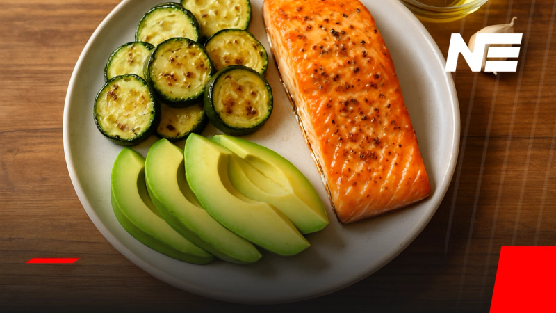 Plato de salmón al horno con zapallo italiano y palta fresca, receta keto para almuerzo o cena, emplatado sobre mesa de madera con luz natural