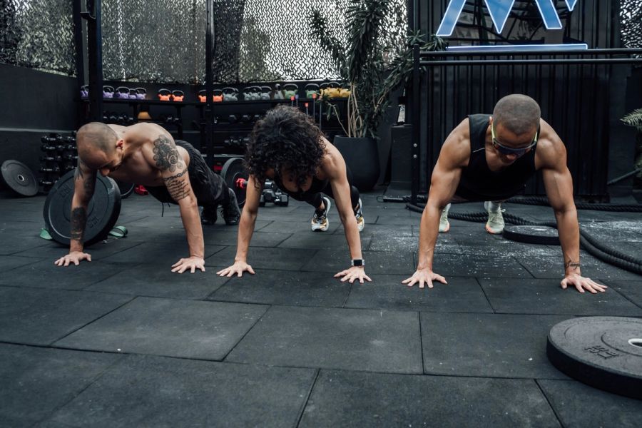 Tres personas haciendo flexiones de brazos en el gimnasio