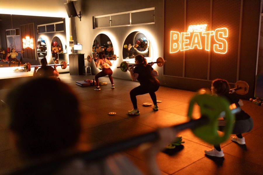 Grupo de Body Pump en sentadilla con la barra sobre los hombros