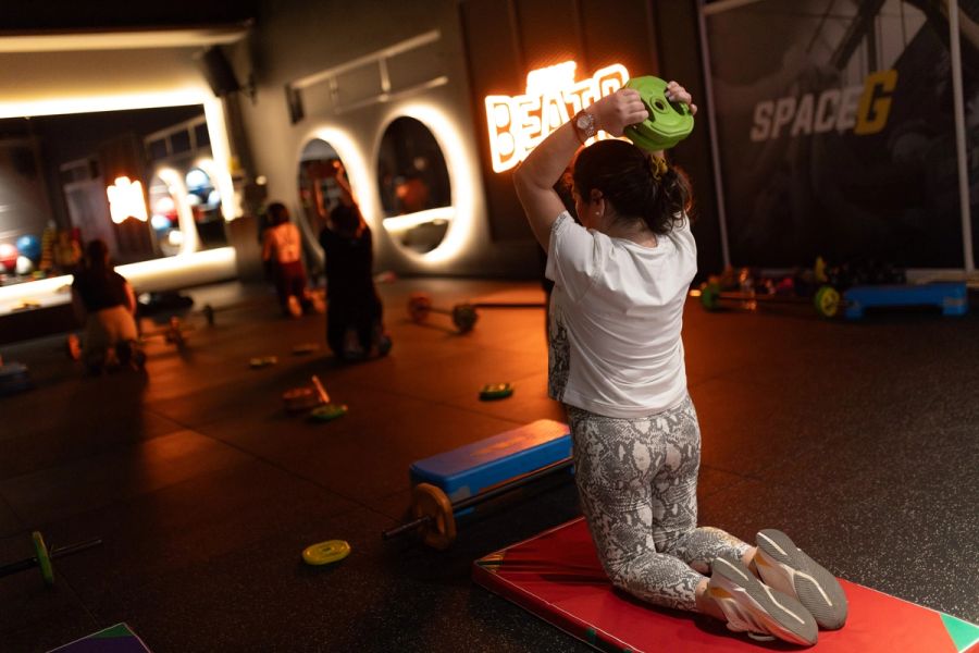Alumna de Body Pump trabajando tríceps con un disco sobre la cabeza