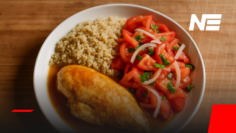 Plato de pollo al jugo con quínoa y ensalada chilena de tomate y cebolla, servido en plato blanco sobre mesa de madera