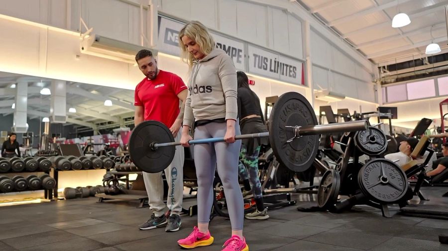 Profesor de Nutre y Entrena corrigiendo la técnica de peso muerto de una socia en la sala de musculación