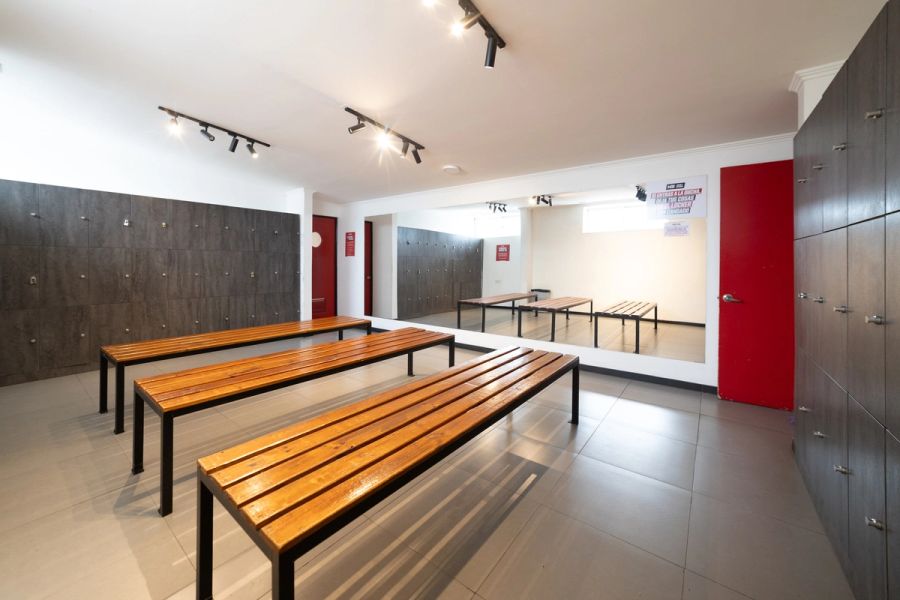 Camarín de Nutre y Entrena con bancas de madera, lockers y espejo de cuerpo entero