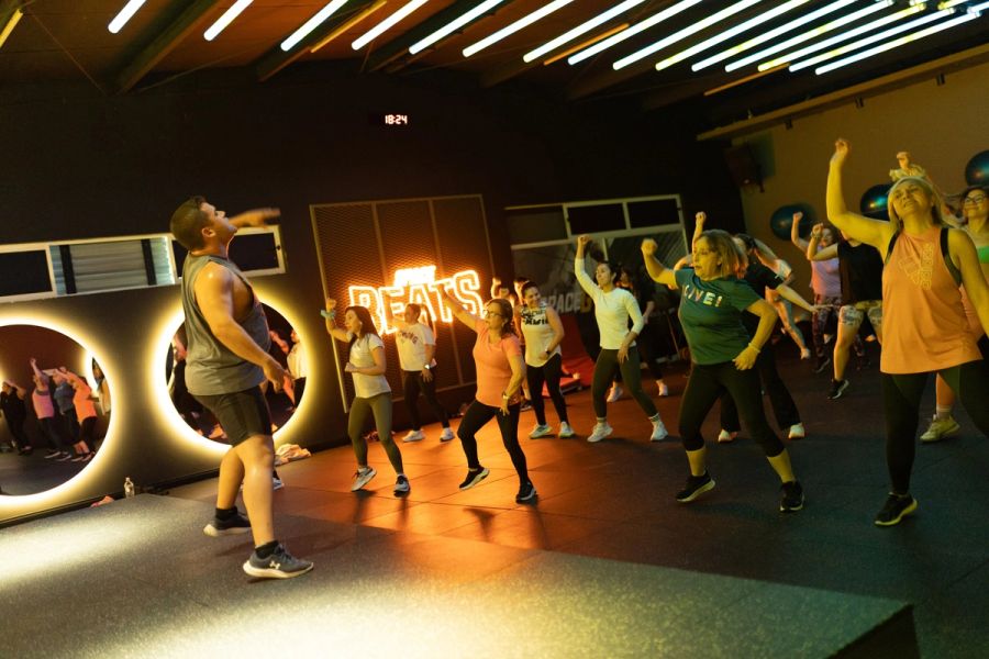 Profesor guiando la coreografía de Zumba frente al grupo en la sala Beats