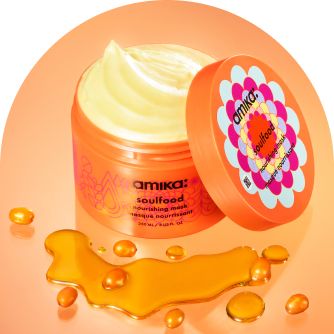 image of a container of amika soulfood nourishing mask with the lid next to the container so that the product mask is exposed. In front of the container are some sea buckthorn berries, this product's hero ingredient.