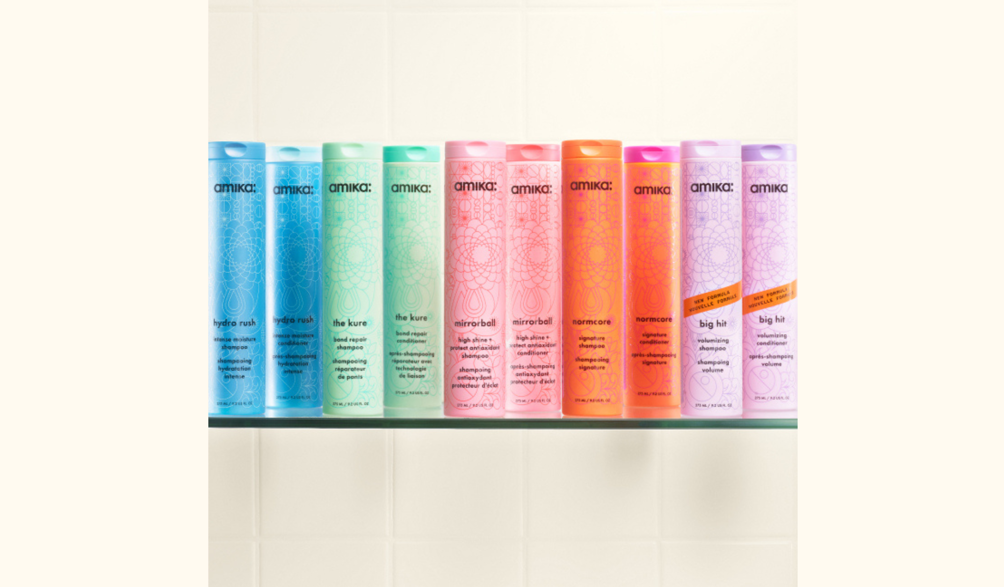 a collection of amika shampoo and conditioners displayed on a glass shelf