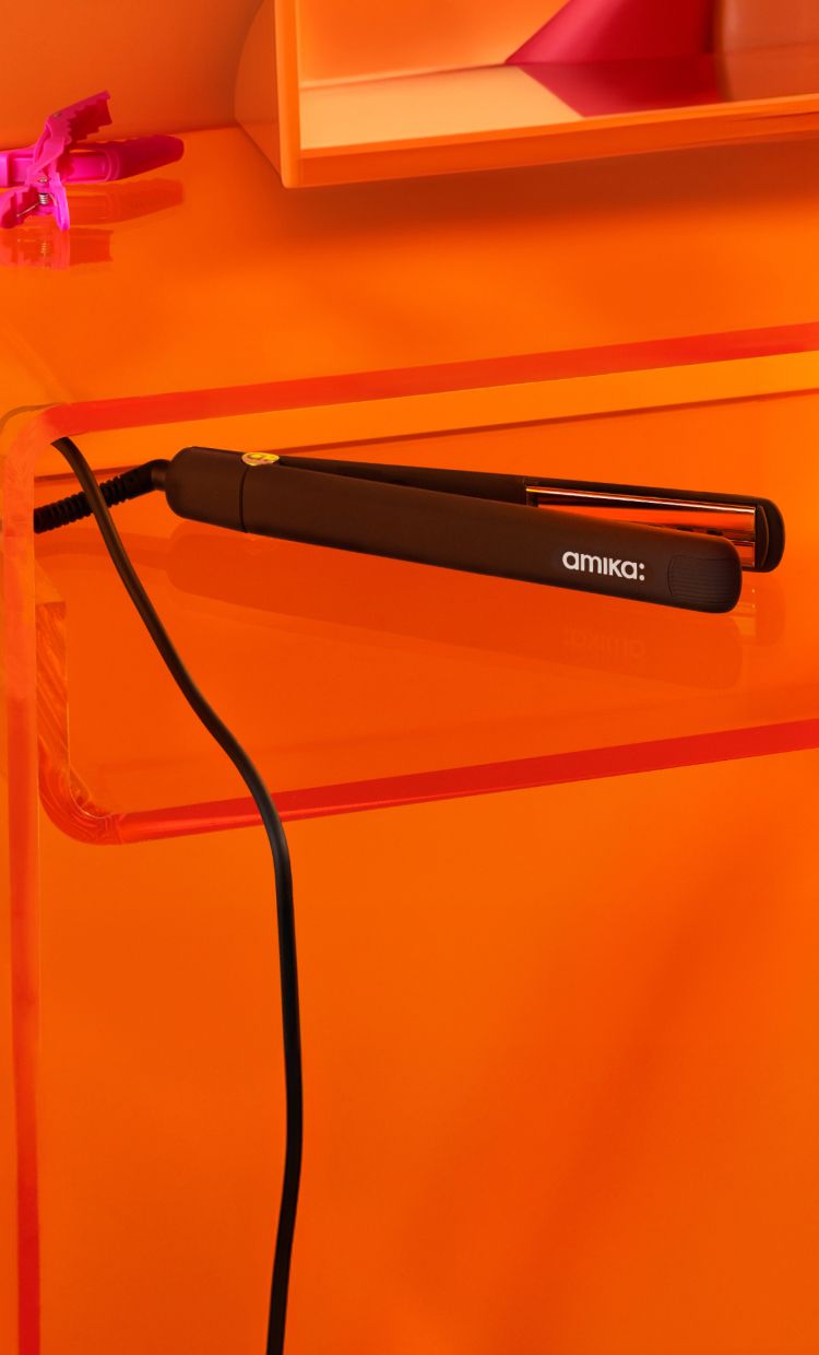 amika flat iron on an orange table