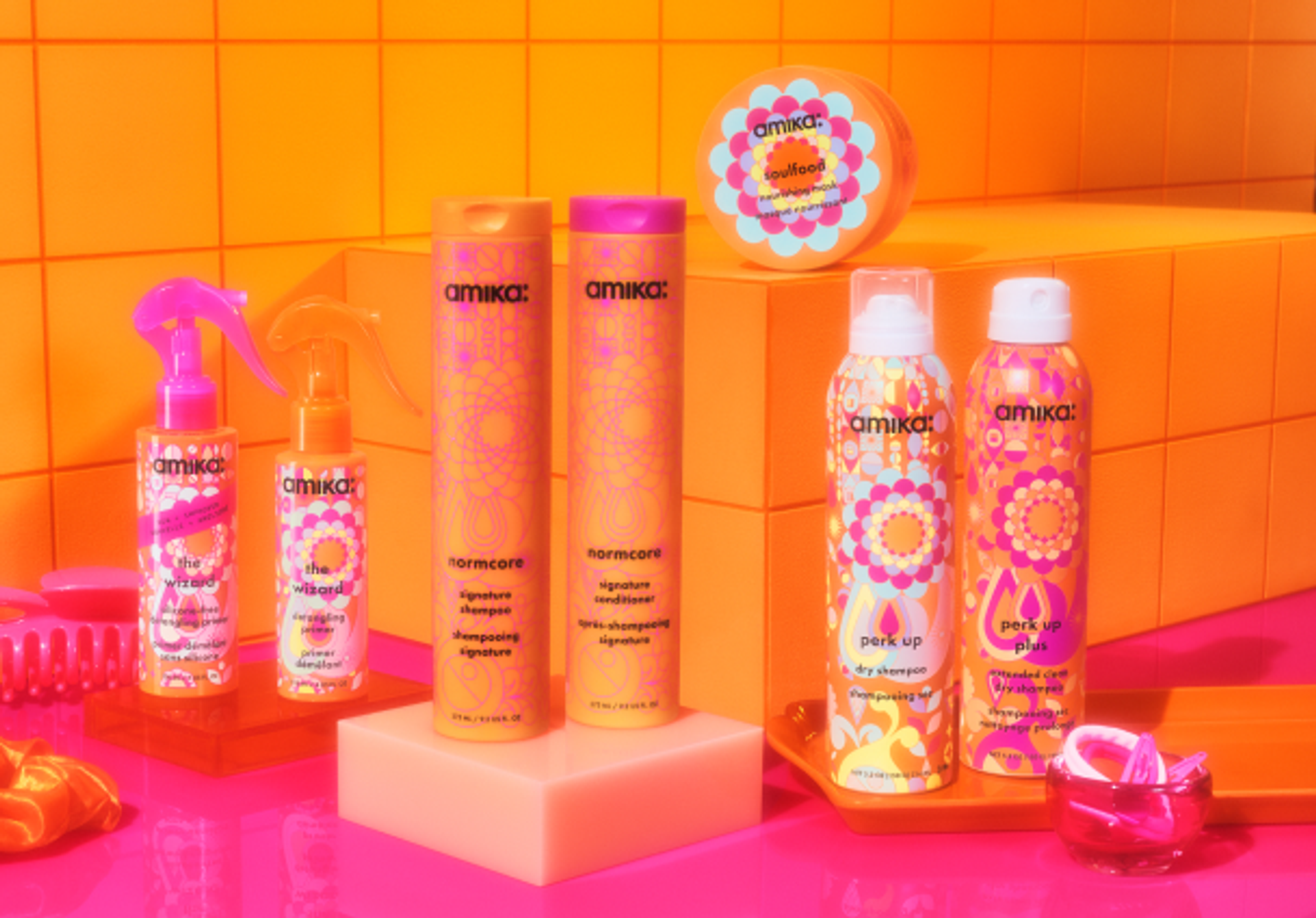 amika signature collection products on a pink counter against an orange tiled background