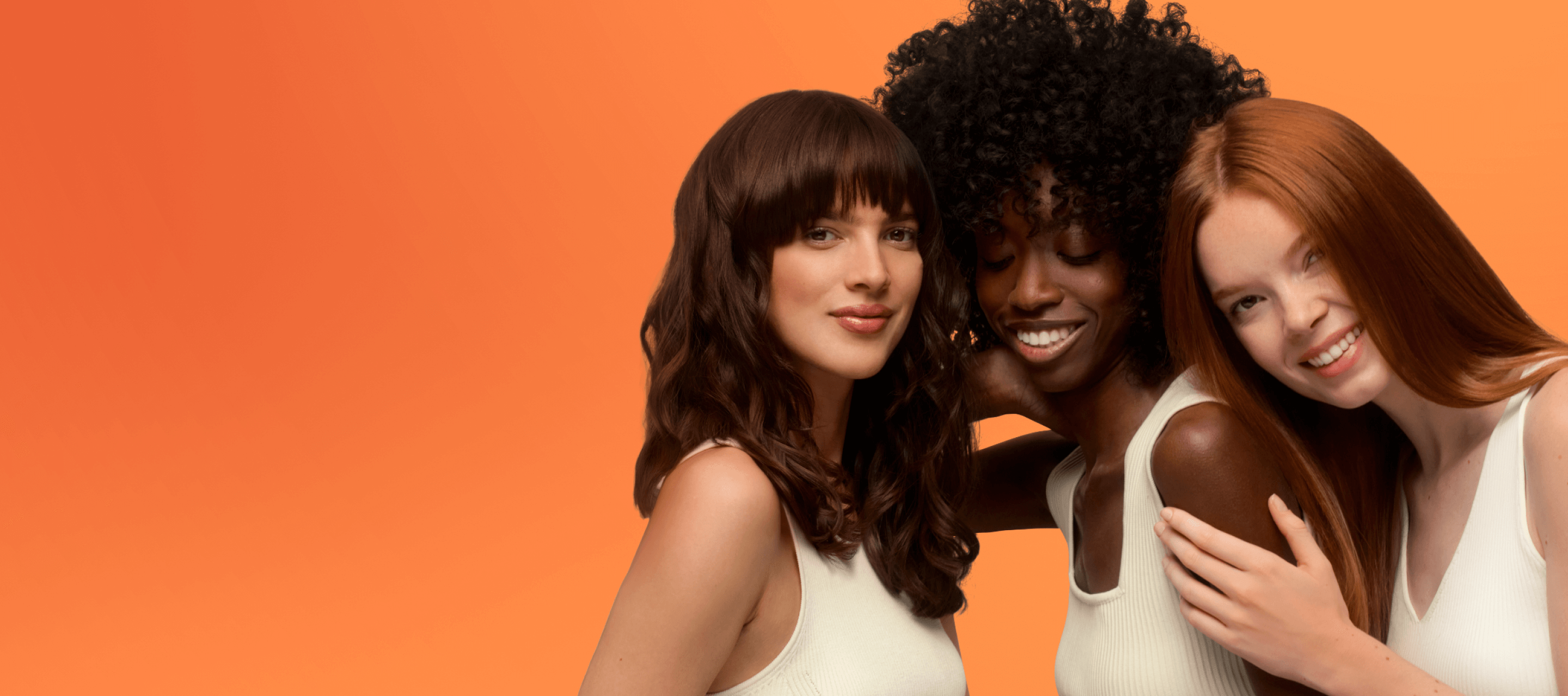 three models embracing each other stand against an orange background